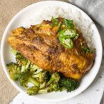 a round bowl with rice, cooked broccoli, and a oven baked indian catfish
