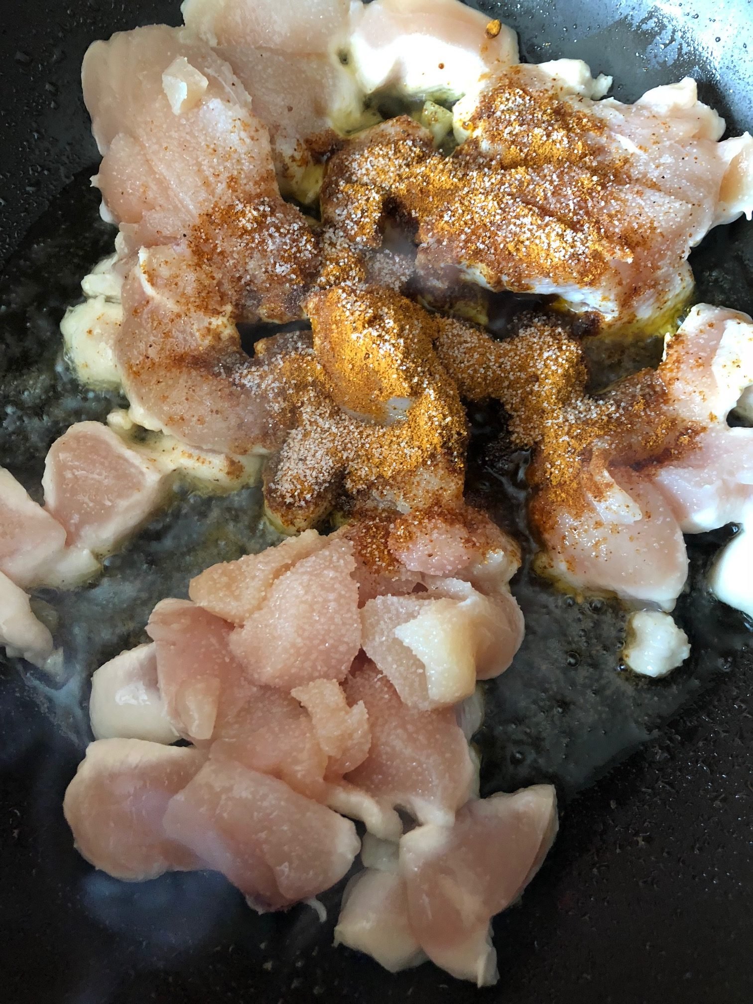 chicken with indian spices being cooked in a non stick pan