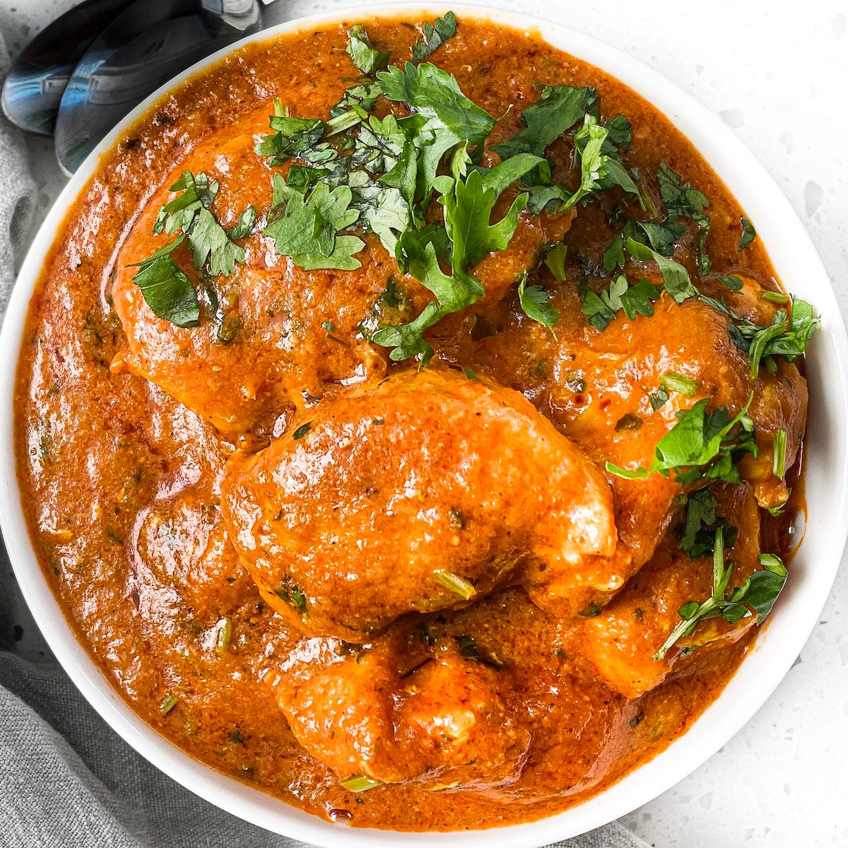 a round bowl with chicken tikka masala and cilantro on top