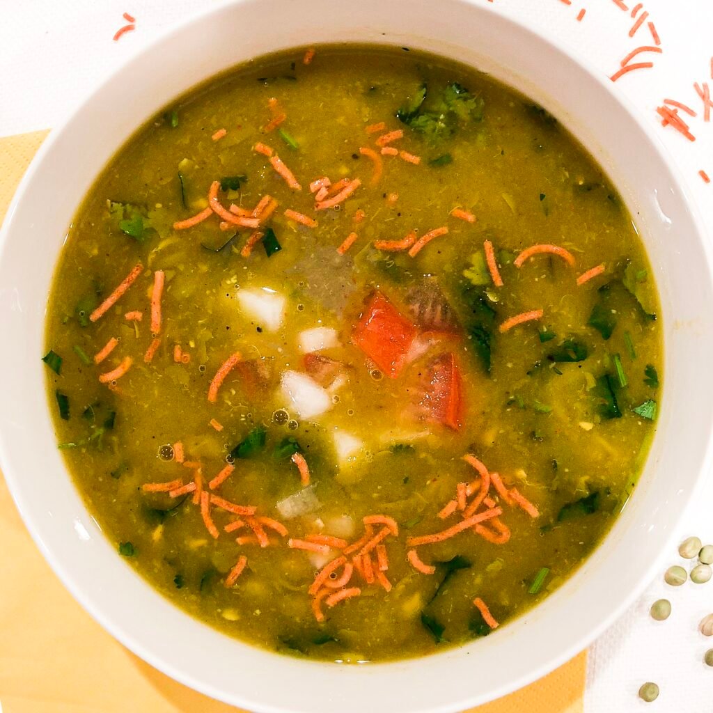 sev and cilantro in a bowl full of green soup