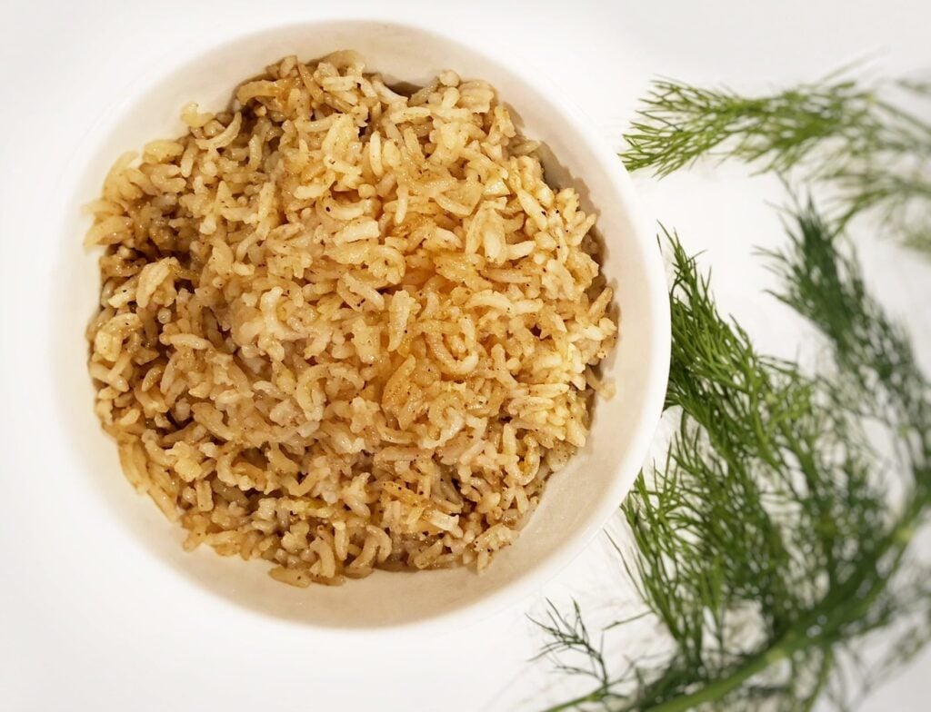 flavored rice in a bowl with dill on the side