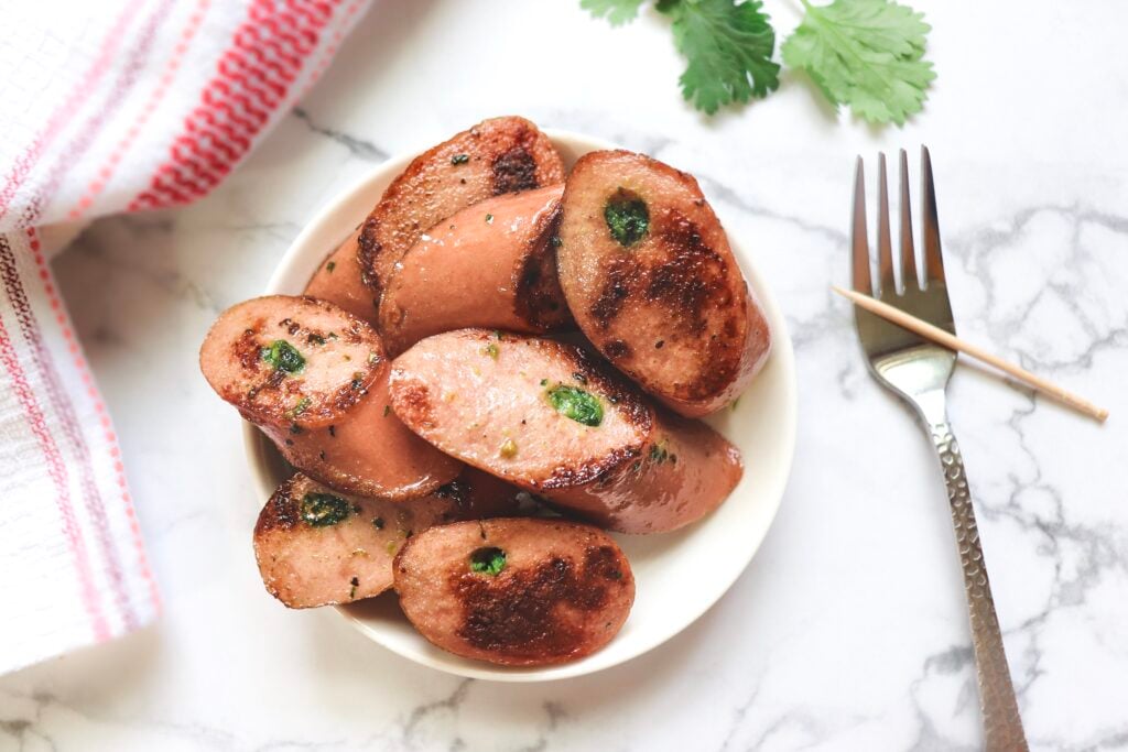 hot dogs that are spicy witch chutney on a plate and a fork next to it