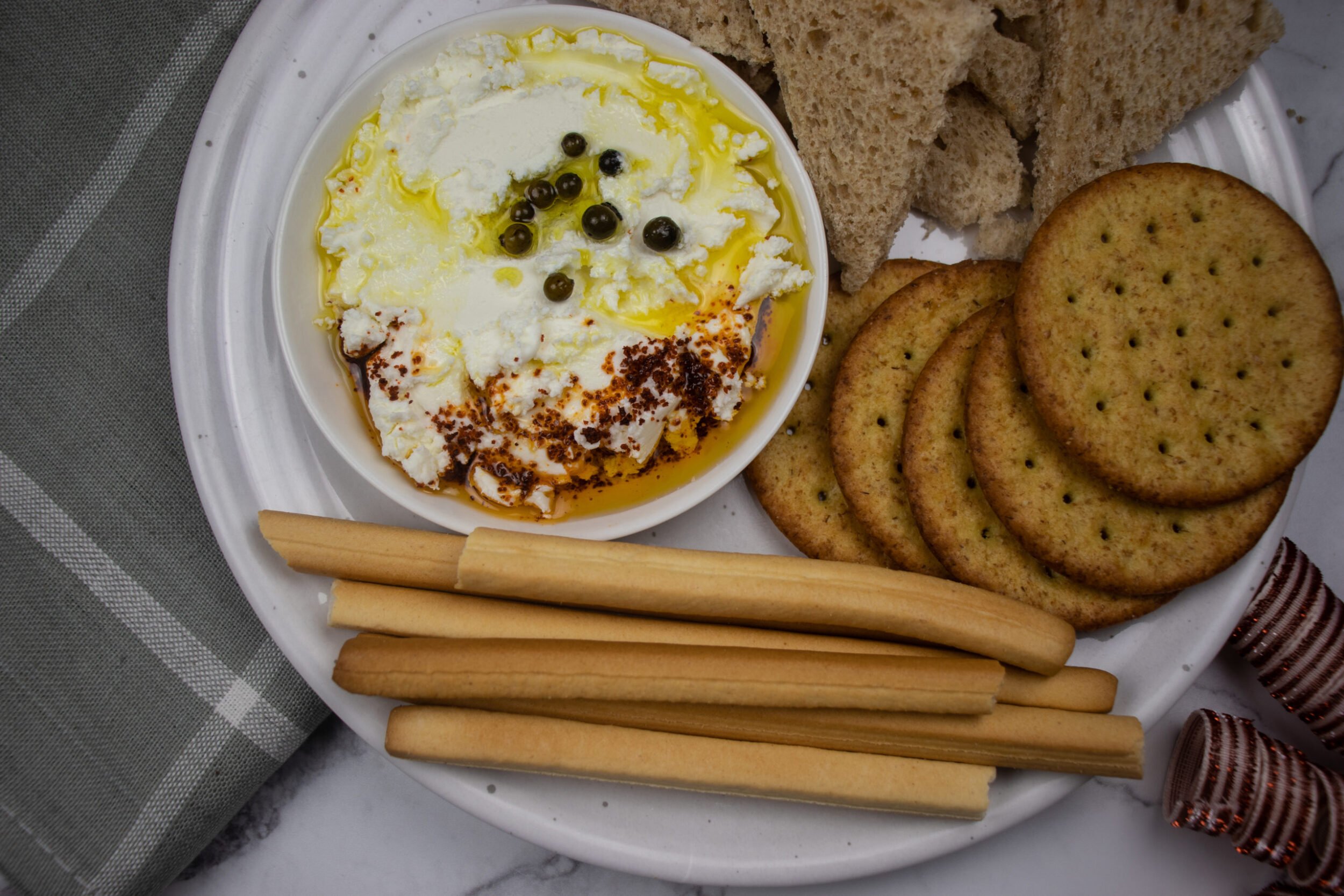 a yogurt dip with spicy pepper on top and crackers next to it