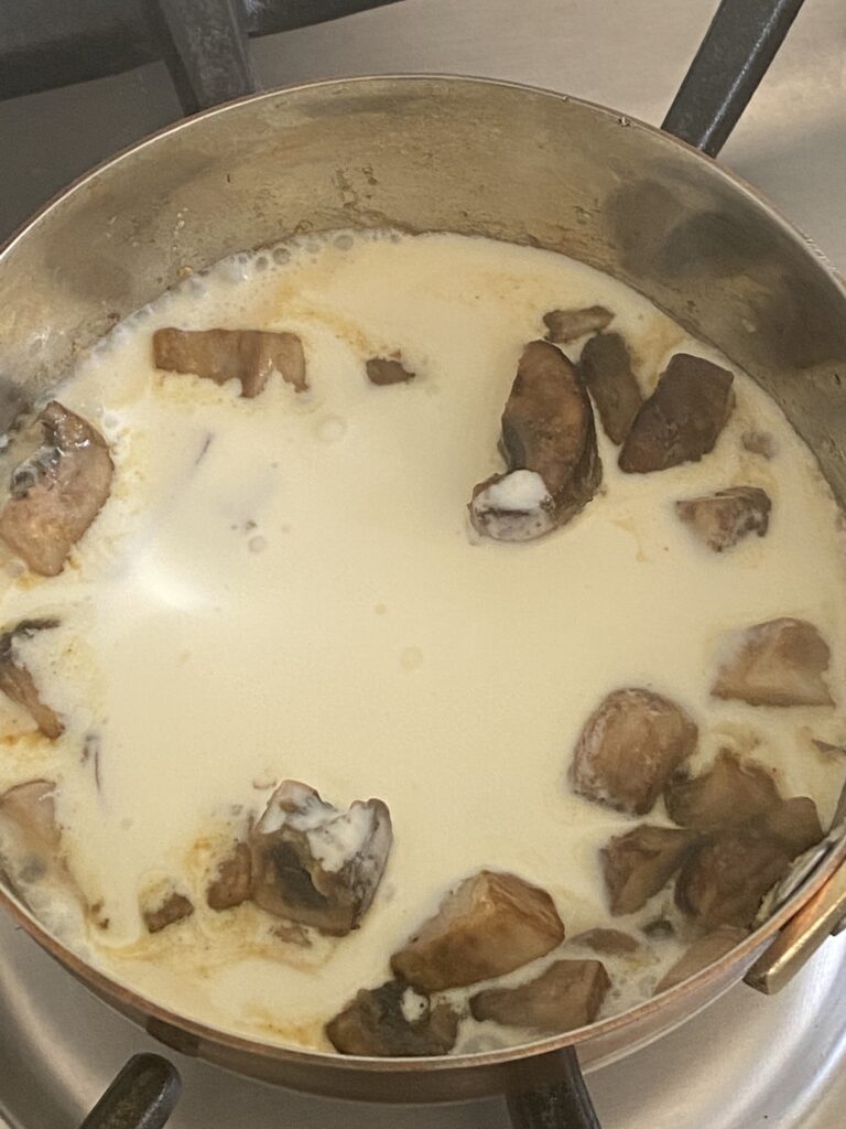 cream poured into a sauce pan with mushrooms