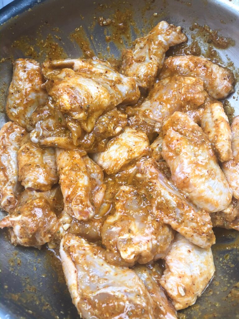 chicken wings with hot sauce and cumin powder coriander powder mixed together for marinating