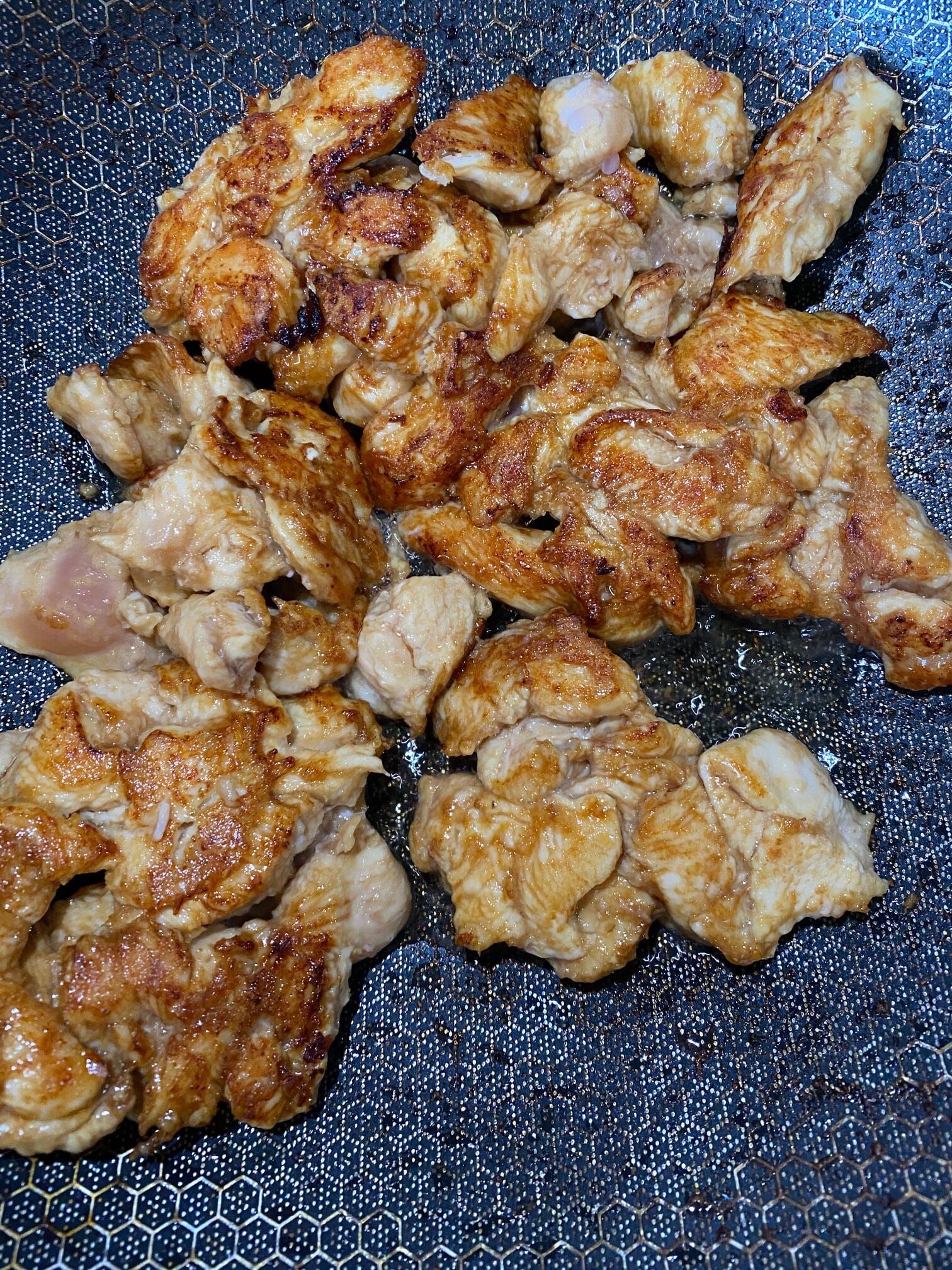 chicken cooked with corn starch, soy sauce, and spices in a wok