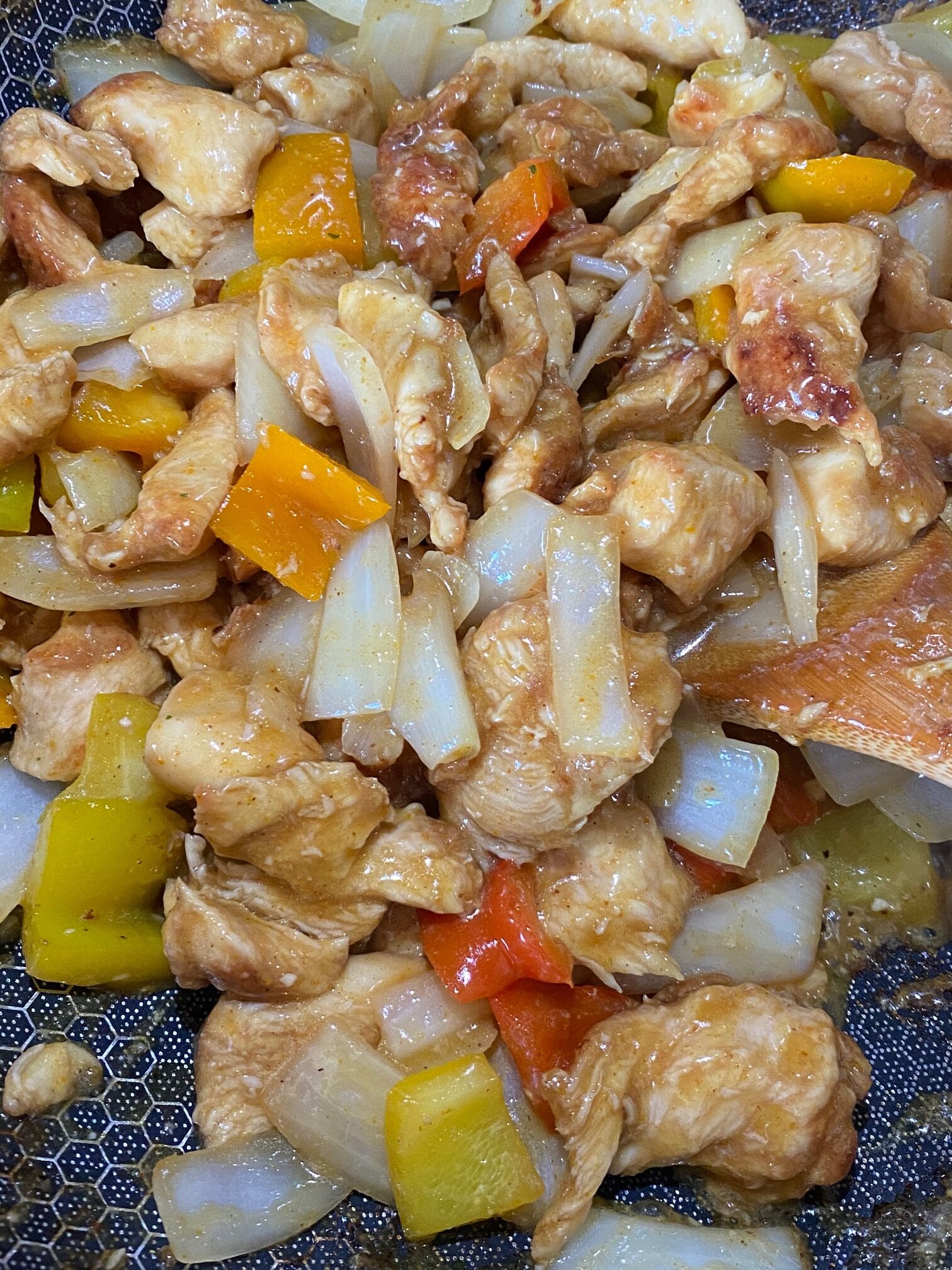chicken being cooked in a hexclad pan with onions and peppers