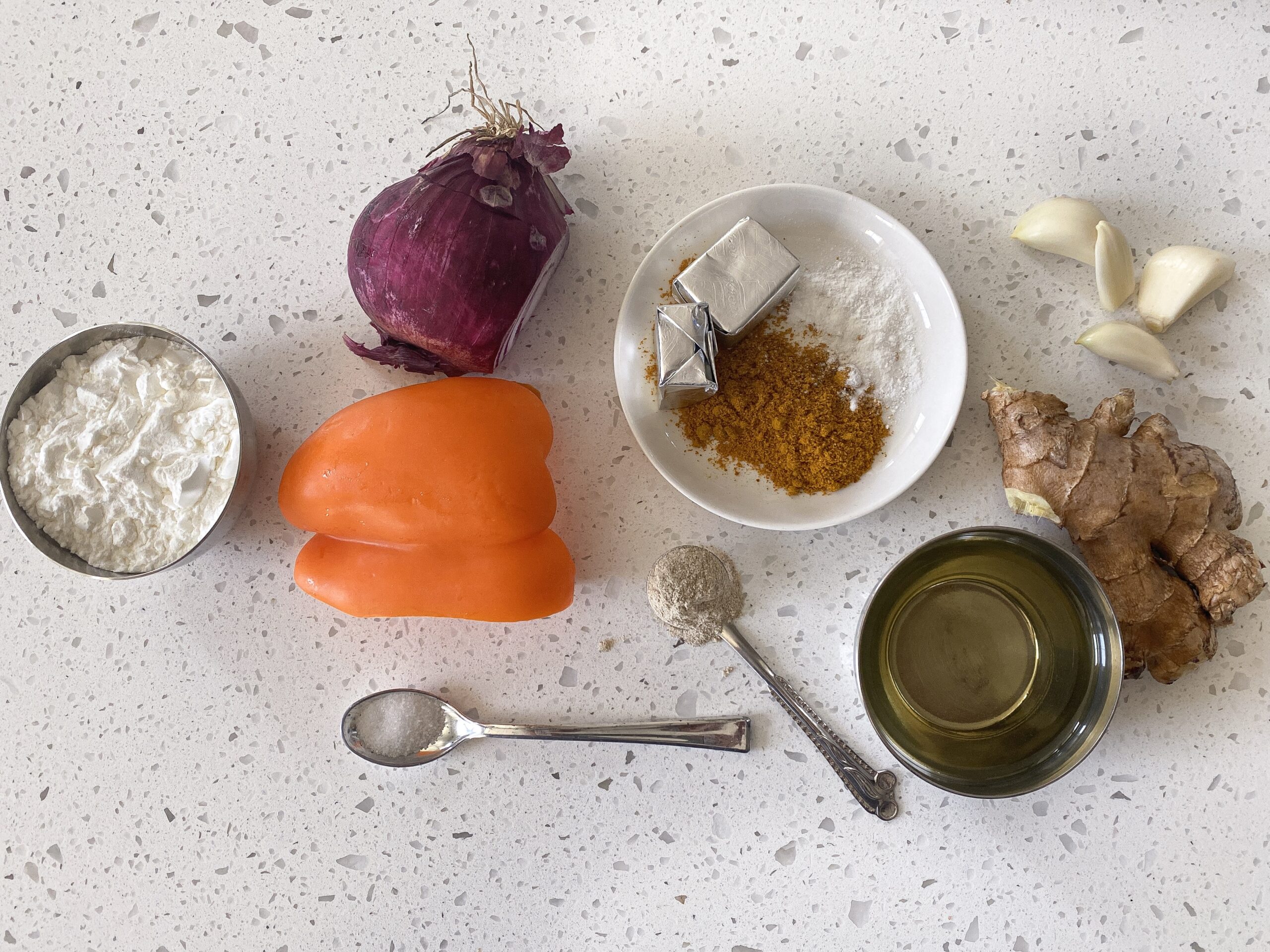 Ingredients for indo chinese chicken curry layed out bell pepper, onion, curry powder, corn starch, oil, and spices