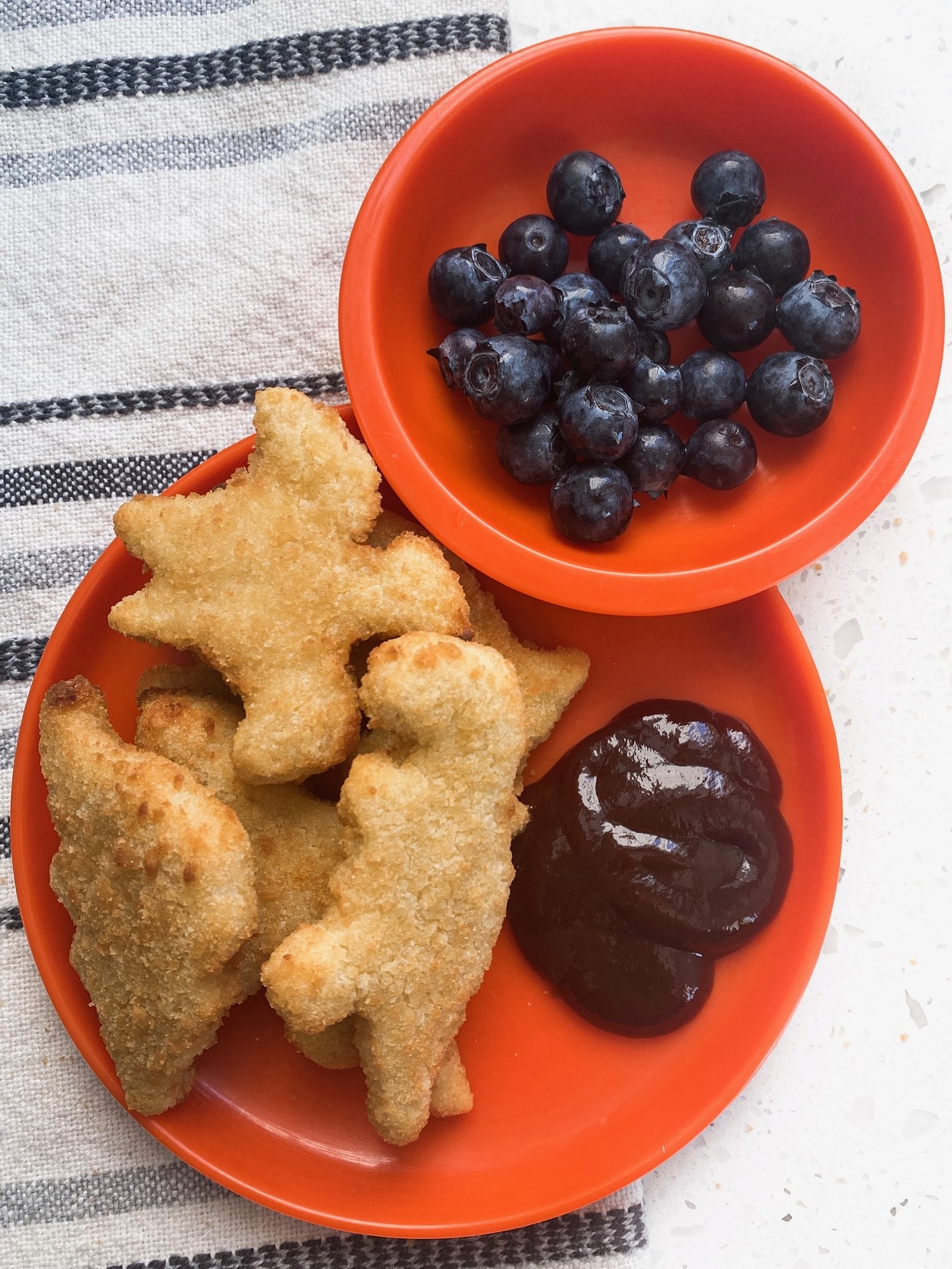 blueberries, bbq sauce, and chicken nuggets on an orange plate