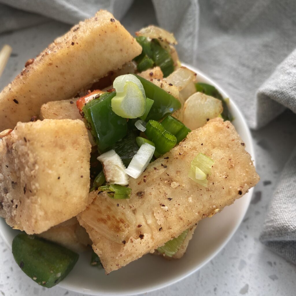 bowl full of tofu that is crisp with onions and peppers