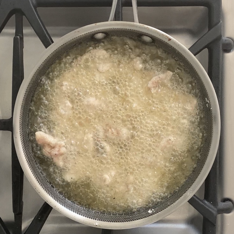 frying battered chicken in a pan