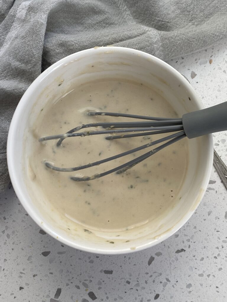 whisking the greek sauce together