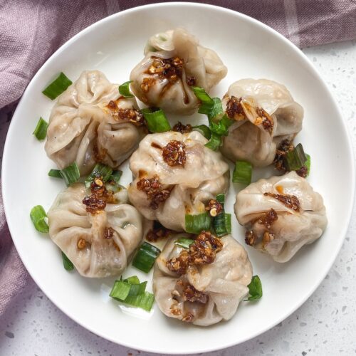 vegan momos in a place with scallions and red chili oil over it