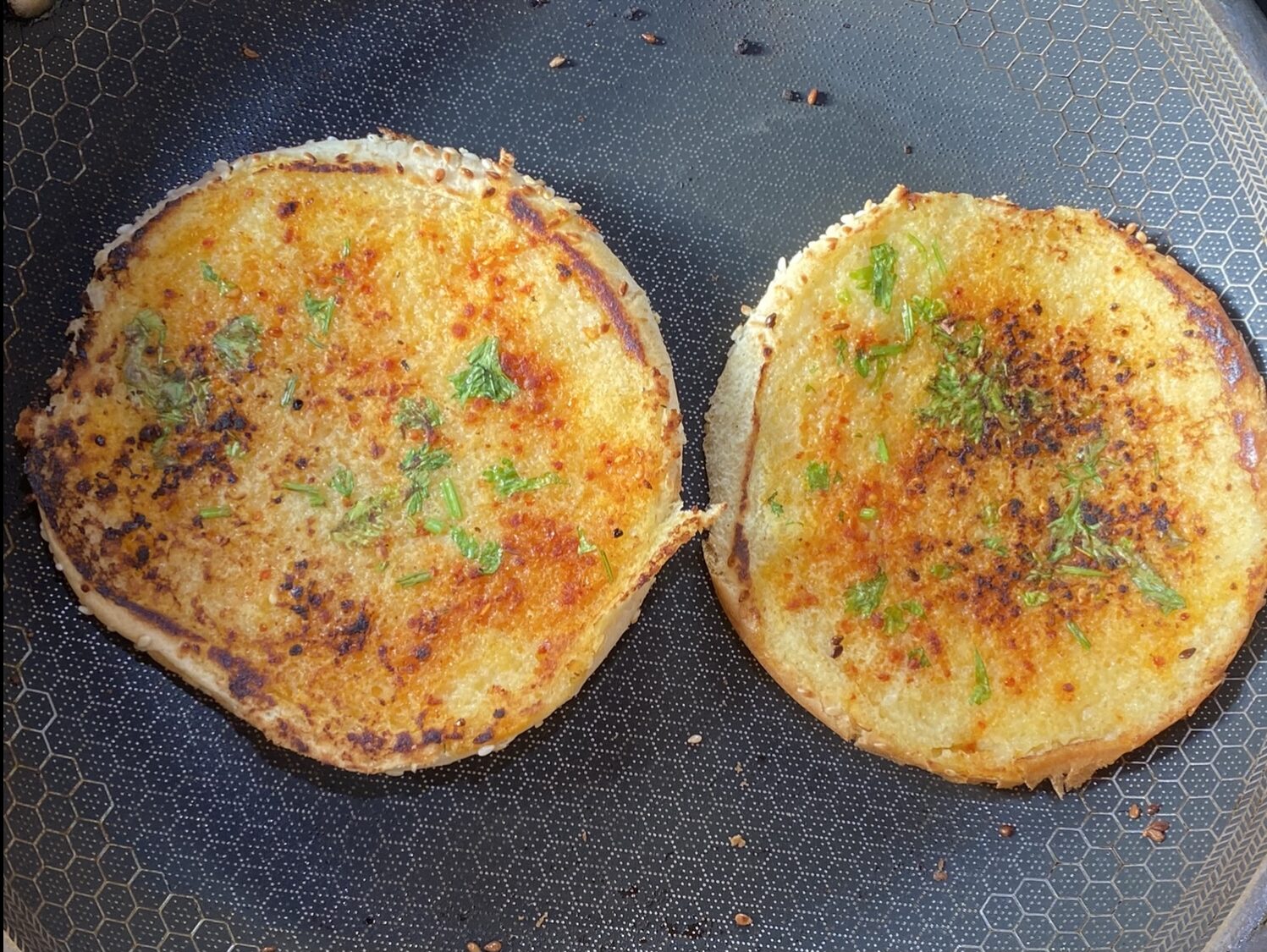 grilled burger bread in a pan with butter, red chili powder, cilantro