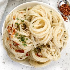 tahini pasta in a bowl with parsley and red chili flakes on top